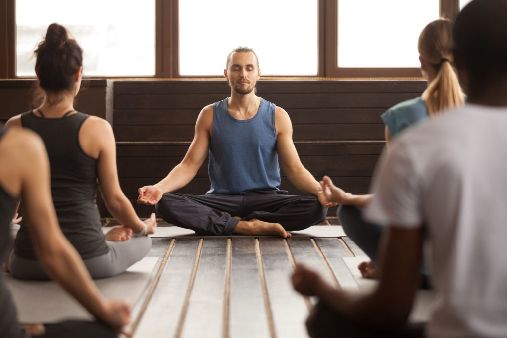 Groep van jonge sportieve mensen in meditatie houding